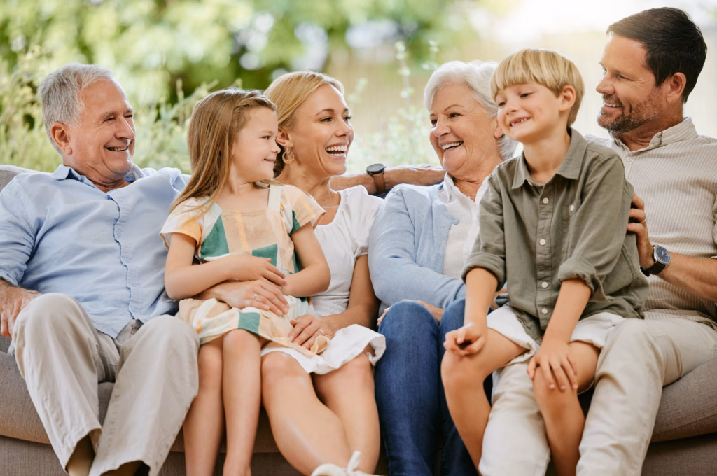 Happy and smiling multi generation caucasian family sitting close together on the sofa at home. Happy adorable children bonding with their mother, father, grandfather and grandmother on a weekend.