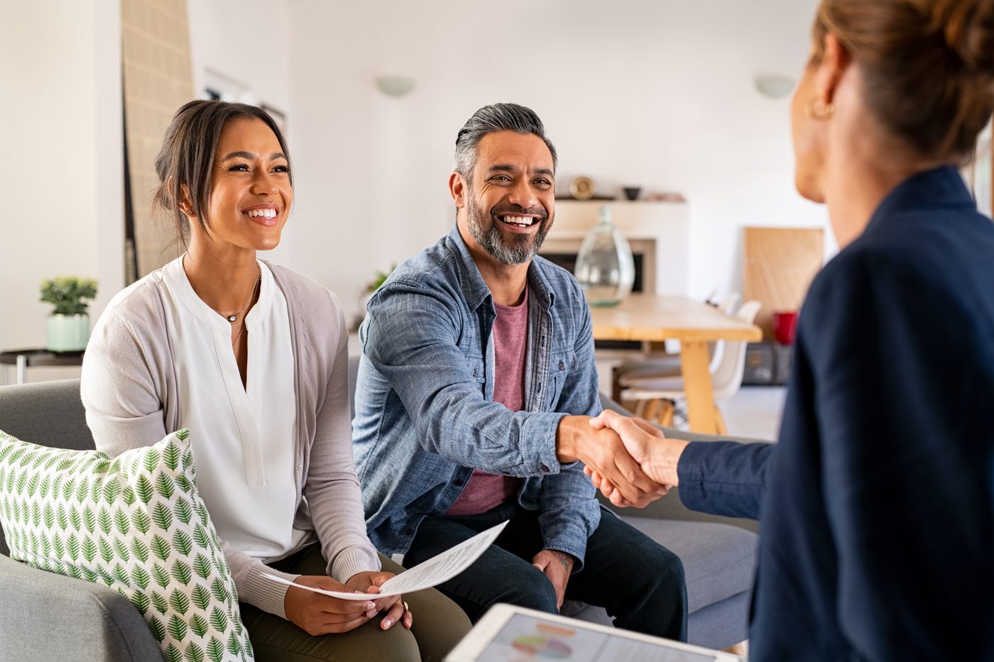 A couple shaking hands with their adviser at home