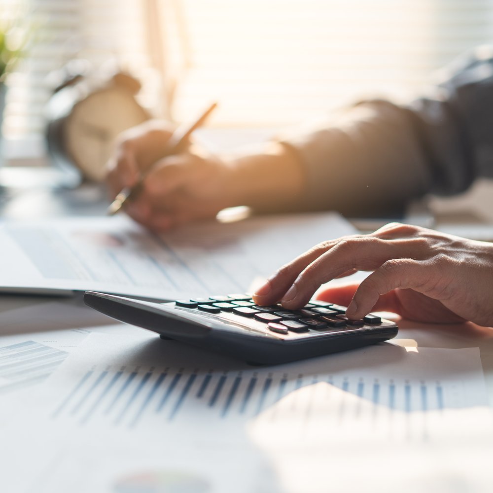 Hands using a calculator over financial paperwork